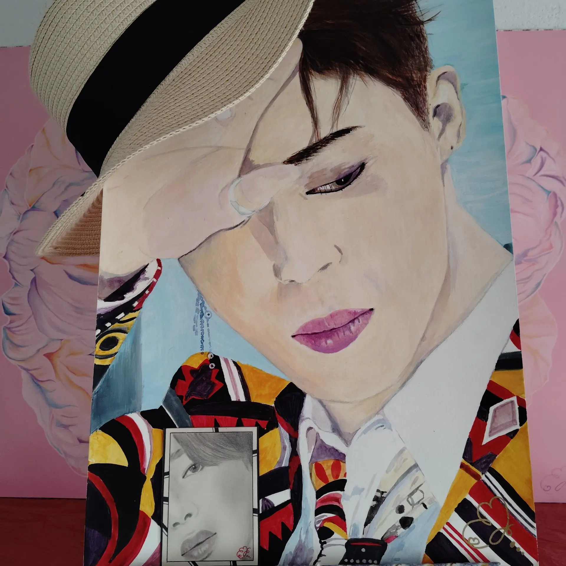 Portrait of Jimin from BTS in a colourful suit. The portrait is wearing a hat. There is also a tiny black and white portrait of Jimin in the picture.